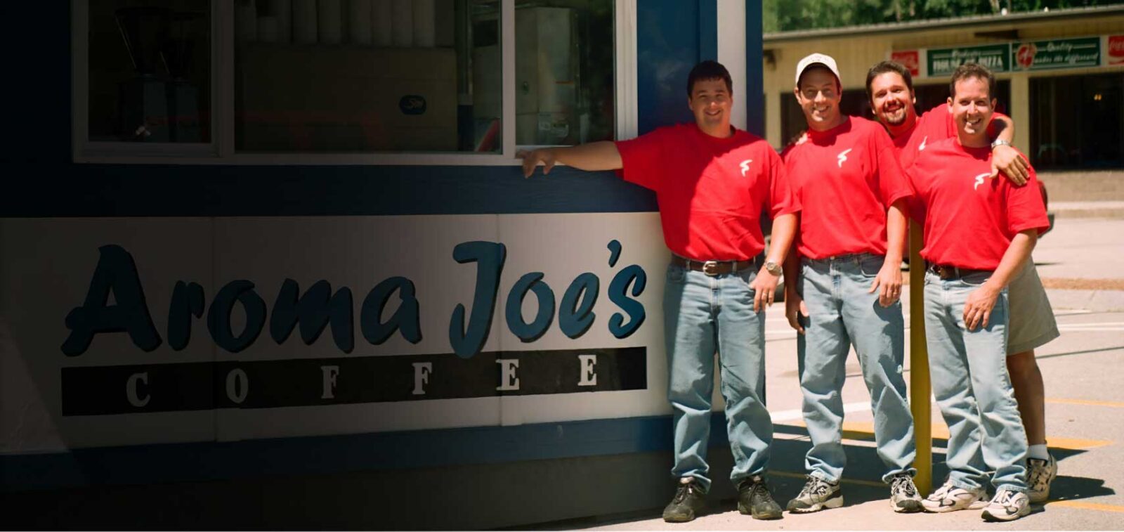 A picture of the founding cousins. All male all dressed in red T-shirts in front of an aroma Joe's location.